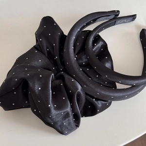 Close-up of black satin polka dot headband and scrunchie set with smooth texture