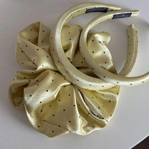 Close-up of yellow satin polka dot headband and matching oversized scrunchie set