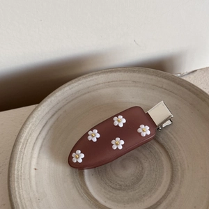 Détail de la pince à cheveux en acrylique avec fleurs 3D blanches et perles dorées