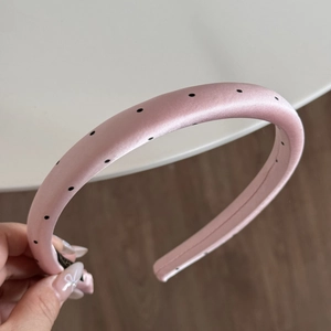 Detailed shot of a pink padded headband with black polka dots on high-quality satin