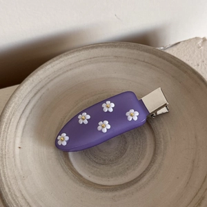 Vue détaillée d'une barrette à cheveux violette en acrylique avec petites fleurs blanches