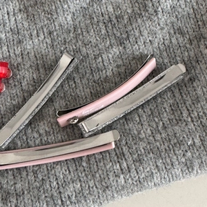 Detail of pink and silver hair clips featuring loved engraving on gray knit background