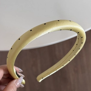 Detailed view of light yellow polka dot headband with silk-like satin fabric
