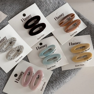 Set of six colorful oval acetate hair clips on white display cards for daily styling