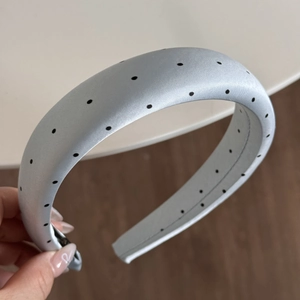 Detail of light blue padded headband with black polka dots and soft satin fabric finish