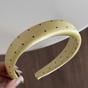 Close-up of a light green polka dot satin headband with thick padded 3D design texture