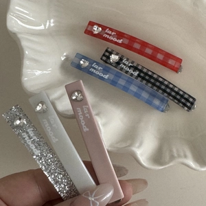 Detail of colorful plaid and solid hair clips with heart rhinestone and artistic text