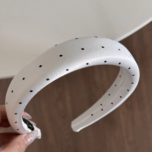 Detail of a thick French retro polka dot headband with white satin fabric texture