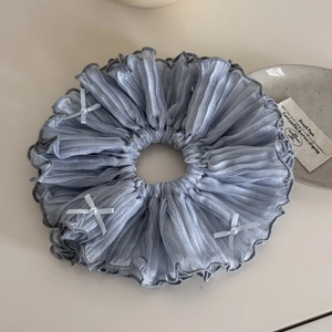 Détail d'un chouchou en mousseline plissée bleu poudré avec nœuds et perles