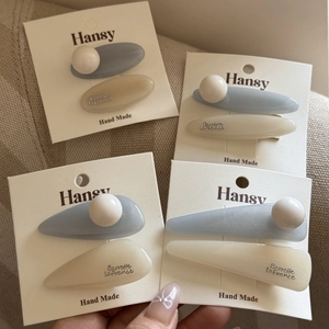 Detail of blue and cream pearl hair clips on display card with handmade branding