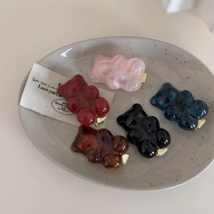 Set aus fünf Harz-Gummibärchen-Haarspangen in Marmor- und Unifarben auf einem Keramikteller