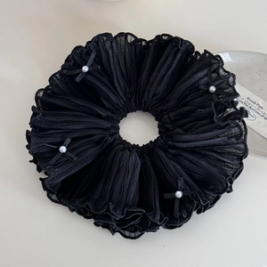 Détail de chouchou en mousseline plissée noire avec nœuds élégants et perles