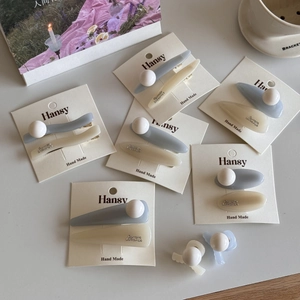Detailed view of Morandi blue and cream hair clips with pearl accents on display card