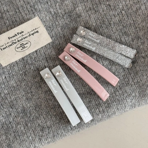 Close-up of set of six rectangular hair clips with heart gems on a grey knit background