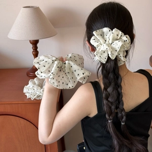 Elastico per capelli in pizzo bianco sporco con cuori neri indossato da una modella in casa