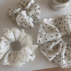 Dettaglio di elastici per capelli in tulle bianco con cuori neri e ricamo in pizzo