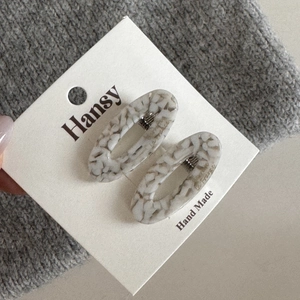 Detail view of the polished marble texture and metal clip on the acetate hairpins