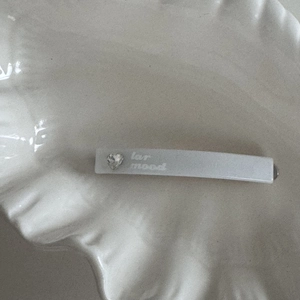 Detail view of a white heart rhinestone hair clip with lar mood lettering