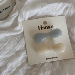 Detail view of blue and cream bow-shaped pearl hair clips on a branded display card