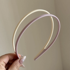 Close-up of flexible cream and lilac headbands with non-slip teeth for secure daily wear