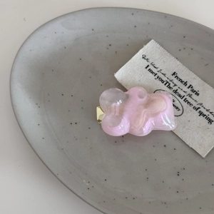 Detailansicht einer rosa-weiß marmorierten Herz-Haarklammer aus Harz auf einem Tablett