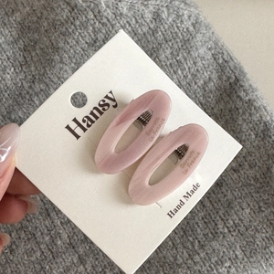 Pair of oval pink acetate hair clips with cloud texture on a white display card