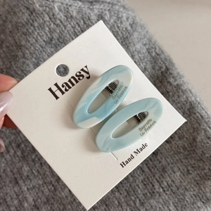 Detailed view of light blue marble acetate hair clips with golden French lettering