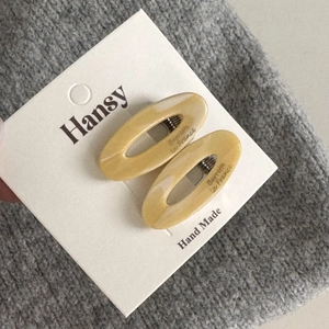 Detailed macro view of mustard yellow marbled acetate hair clips on a soft display card