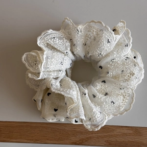 Dettaglio dell'elastico in pizzo bianco con cuori neri ricamati e trama plissettata