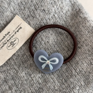 Vue détaillée d'un élastique à cheveux cœur avec strass et motif nœud sur tissu tricot