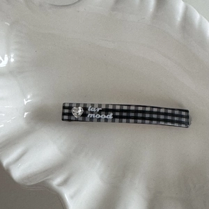 Detailed close-up of a plaid hair clip with a heart rhinestone and lar mood text
