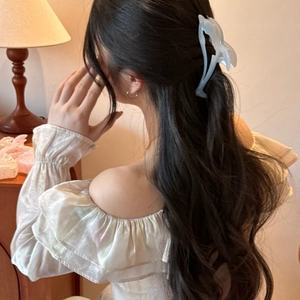 Blue dolphin hair claw clip shown styling long wavy dark hair in a warm home setting