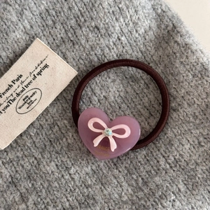 Détail d'un élastique à cheveux marron avec cœur en acrylique violet et nœud rose