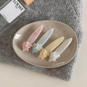 Détail de quatre pinces à cheveux florales avec pétales mats et perles dans un plateau