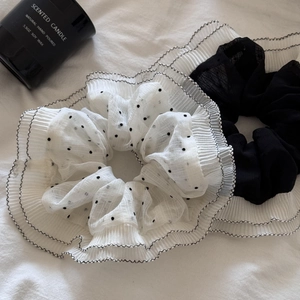 Detail of chiffon polka dot scrunchies with pleated black trim on white fabric
