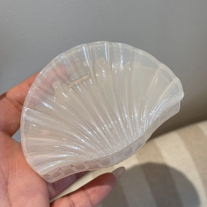 Detailed close-up of shell-shaped hair claw with pearlescent glitter finish and sturdy metal spring