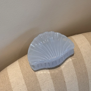 Detailed close-up of light blue shell-shaped hair claw with pearlescent glitter finish