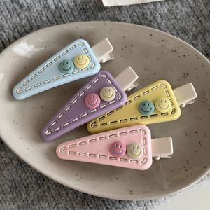 Triangle hair clips in macaron colors with cute smiley faces on a ceramic tray