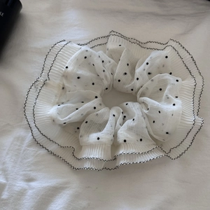 Detail of white mesh scrunchie featuring black polka dots and pleated ruffled edges
