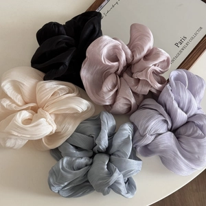 Detailed view of five pearlescent fabric scrunchies in assorted soft elegant colors