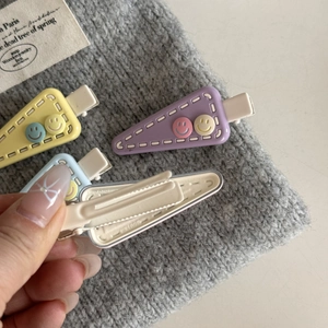 Detail of triangle hair clips with cute smiley faces and durable metal duckbill back