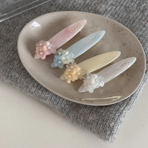 Détail de 4 barrettes à fleurs aux couleurs pastel avec texture marbrée et perles sur plateau