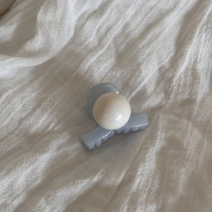 Close-up of a blue matte duckbill hair clip with a large white pearl bead ornament