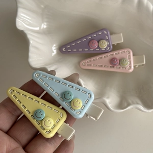 Triangle hair clips in pastel macaron colors featuring cute smiley faces and white stitching