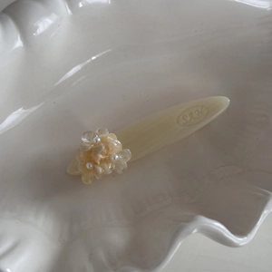 Détail de la pince à cheveux florale crème avec perles et fleurs sur une assiette blanche