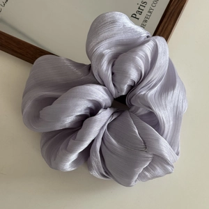 Detailed view of lavender purple satin scrunchie with pleated texture and pearly luster