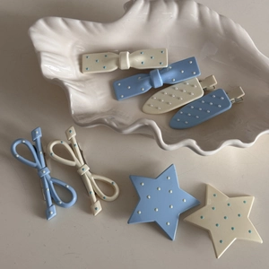 Set di fermagli per capelli con fiocco a pois e stella color crema e blu su piatto