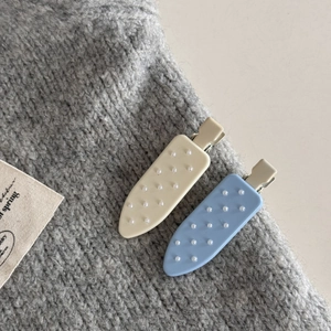 Dettaglio delle mollette per capelli a pois azzurro e beige con perle bianche finte
