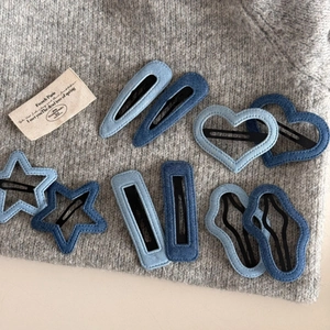 Denim blue fabric hair clips set with star and heart shapes on a grey sweater