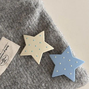 Dettaglio dei fermagli per capelli a stella con pois su sfondo in maglia grigia